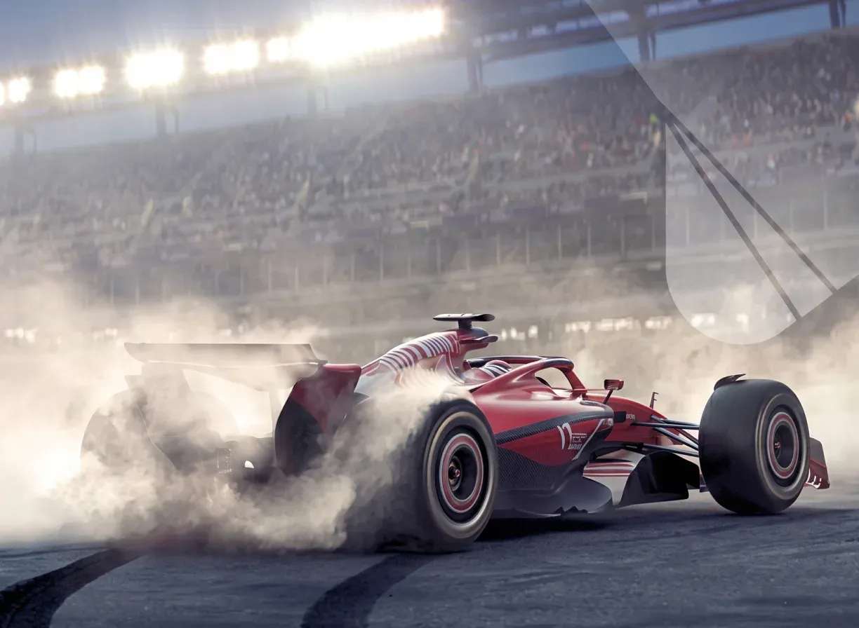 A single-seater race car accelerating out of a corner under floodlights, tyre smoke trailing behind it